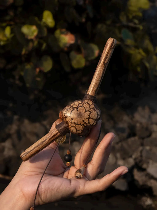 Hand holding a wooden tool with a textured handle against a natural background