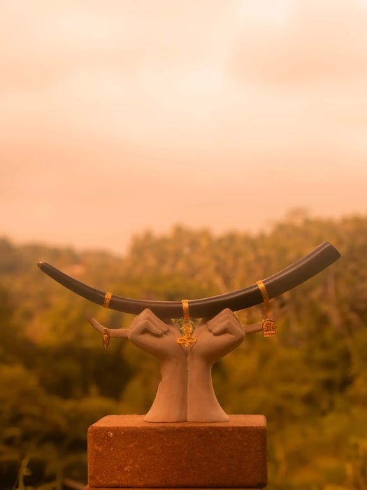 Statue of hands holding a large bull's horn with a blurred natural background