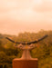 Statue of hands holding a large bull's horn with a blurred natural background