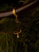 Gold bracelet with a decorative clasp on a wooden surface with greenery