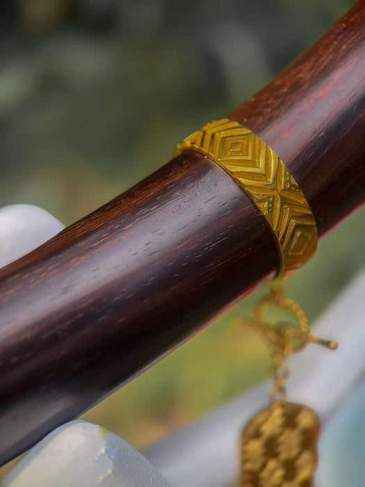 Close-up of a wooden stick with a gold decorative band and hanging charm.