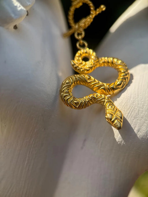 Gold snake-shaped earring on a person's ear