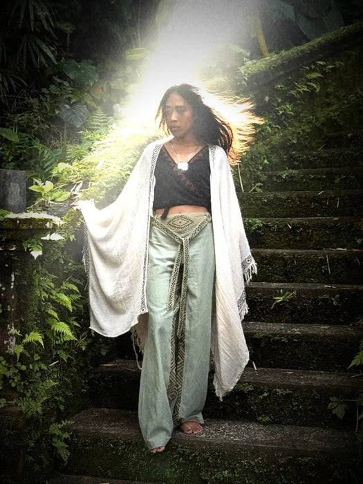 Woman in traditional attire standing on a staircase in a forest setting