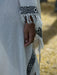 Close-up of a white garment with black geometric patterns and fringes, held by a person.