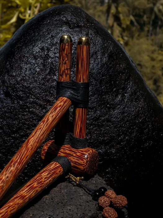 Wooden tools with black bands on a dark stone surface
