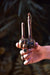 Hand holding a wooden tool with decorative elements against a dark background