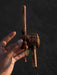 Hand holding a wooden prayer wheel against a dark background