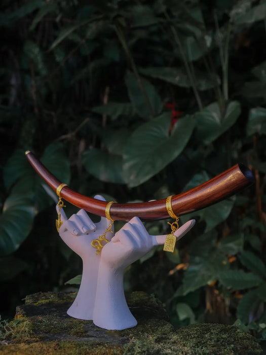 Decorative sculpture of hands holding a bow with a dark green leafy background