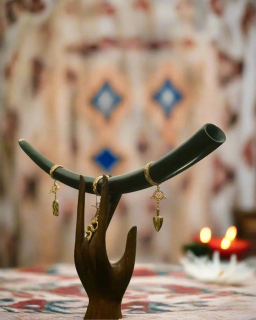 Jewelry stand with earrings against a patterned wall with candles.