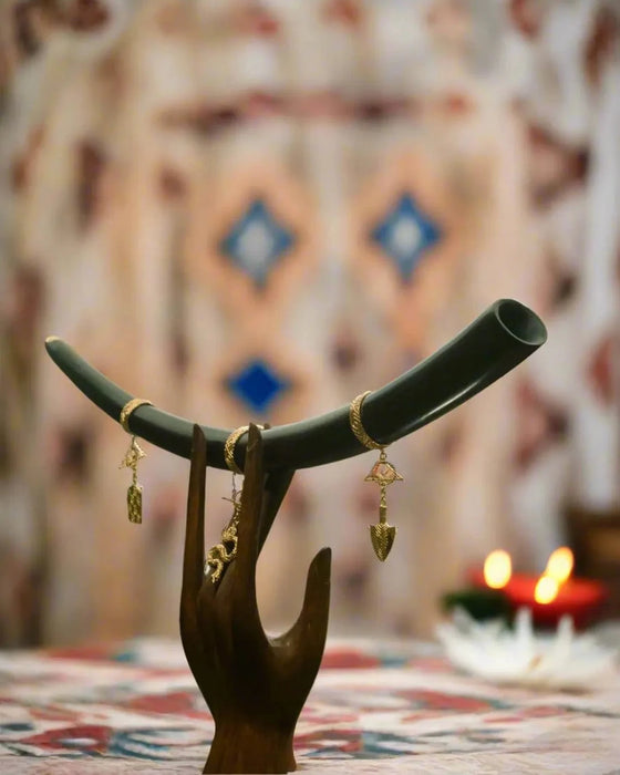 Jewelry stand with earrings against a patterned wall with candles.