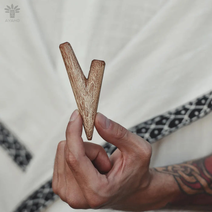 Hand holding a wooden letter 'V' against a neutral background