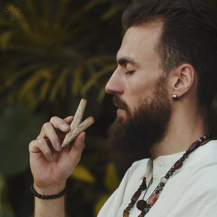Man with a beard holding a piece of wood against a blurred natural background