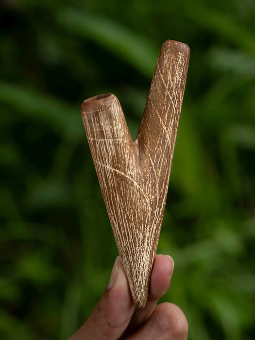 Wooden tool held in a hand with a blurred green background