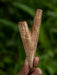 Wooden tool held in a hand with a blurred green background