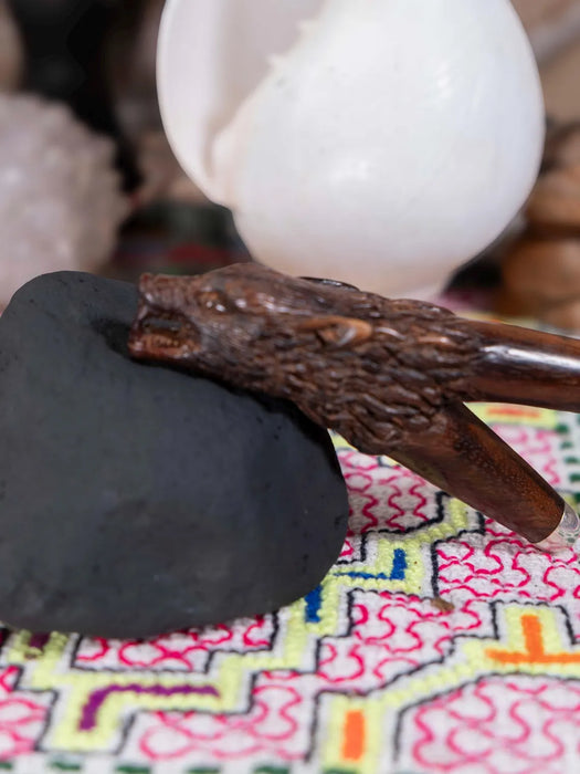 Close-up of a wooden tool held by a gloved hand on a colorful fabric background
