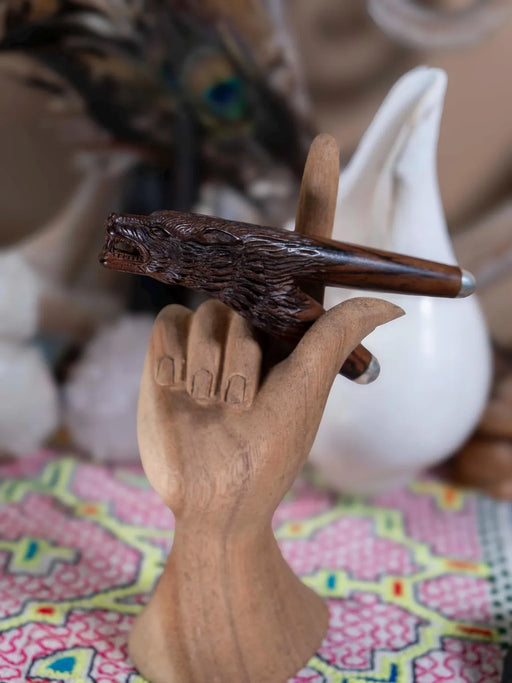 Wooden hand holding a carved object with a blurred background