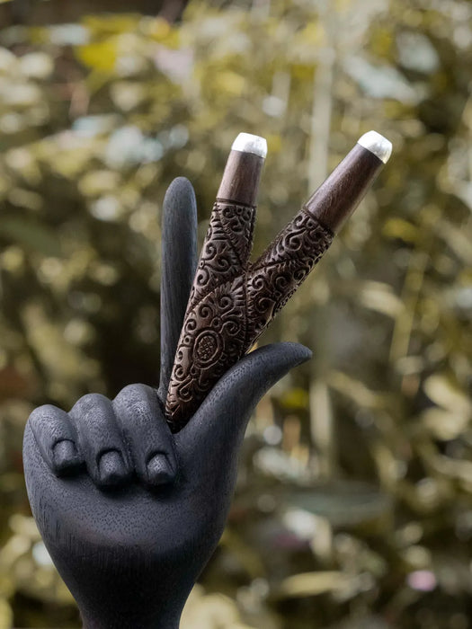 Decorative hand with intricately designed fingers against a blurred natural background