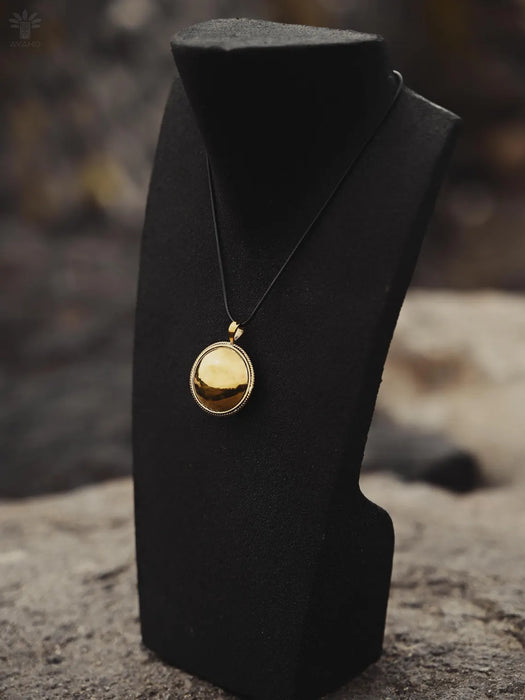Gold necklace on a black mannequin bust with a blurred natural background