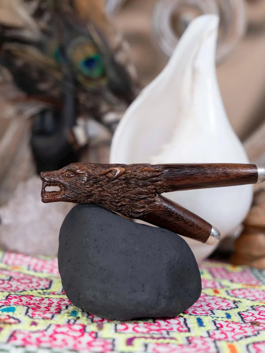 Wooden smoking pipe with dragon design on a black stone, blurred background