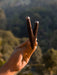 Hand holding two intricately designed wooden sticks against a blurred natural background
