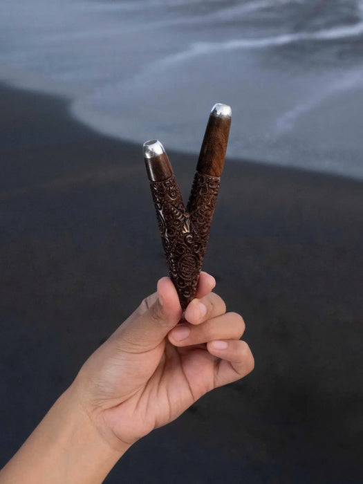 Hand holding a decorative object against a dark water background