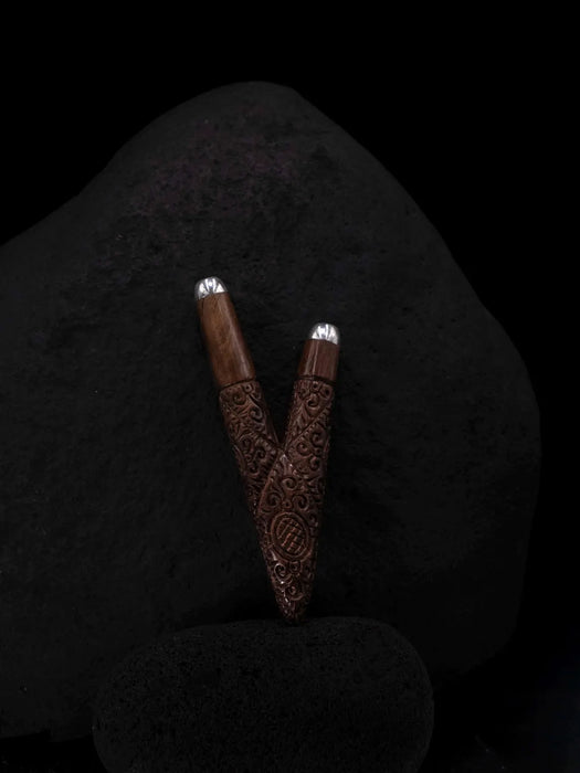 Two wooden incense holders with intricate carvings on a dark stone surface