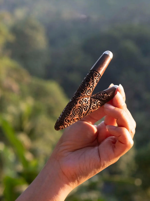 Hand holding a decorative object against a blurred natural background