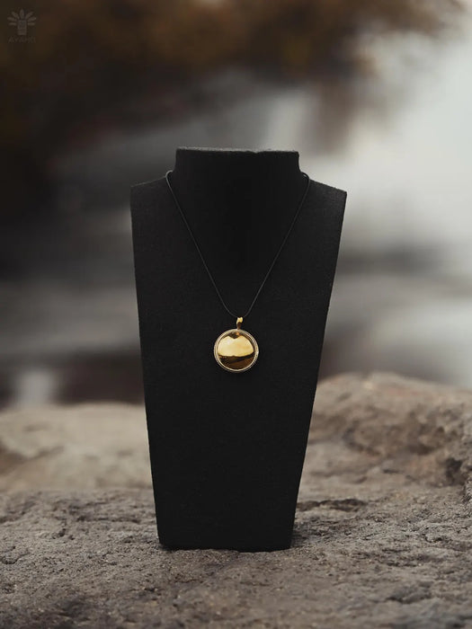 Gold necklace on a black stand with a blurred natural background