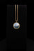 Gold necklace with a blue pendant on a black background