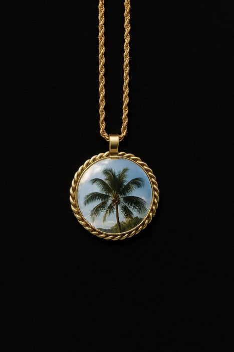 Gold necklace with a pendant featuring a palm tree design on a black background