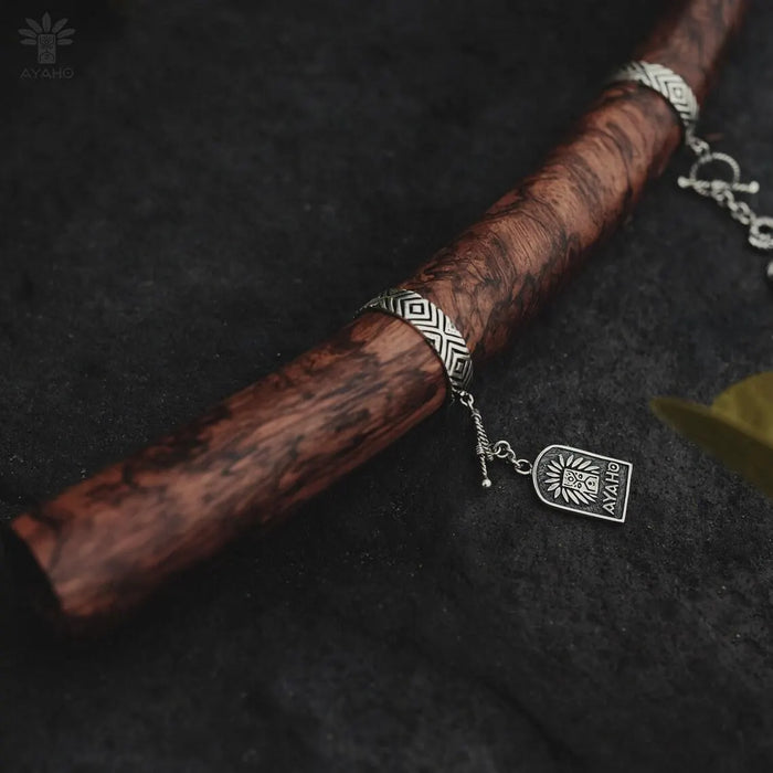 Silver bracelet with a pendant on a wooden stick against a dark background