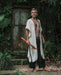 A man stands in a forest, his demeanor calm and grounded, wearing a Boho tribal cotton poncho, embodying a unisex, earthy shamanic style.