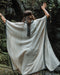A person enveloped in a handmade Boho tribal cotton poncho, embracing the serenity of nature at a waterfall, reflecting a unisex shamanic clothing style