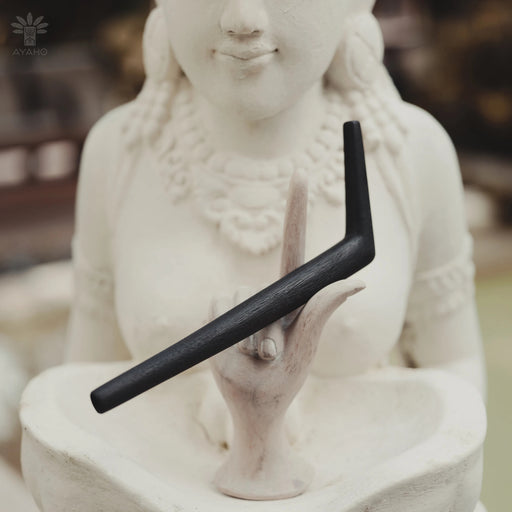 Smoothly polished tepi pipe made of natural rosewood resting on ethnic-patterned fabric, showcasing beautiful wood grain texture
