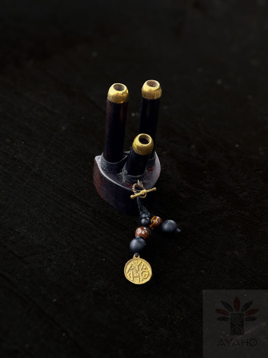 Decorative item with three cylindrical elements and a pendant on a dark background