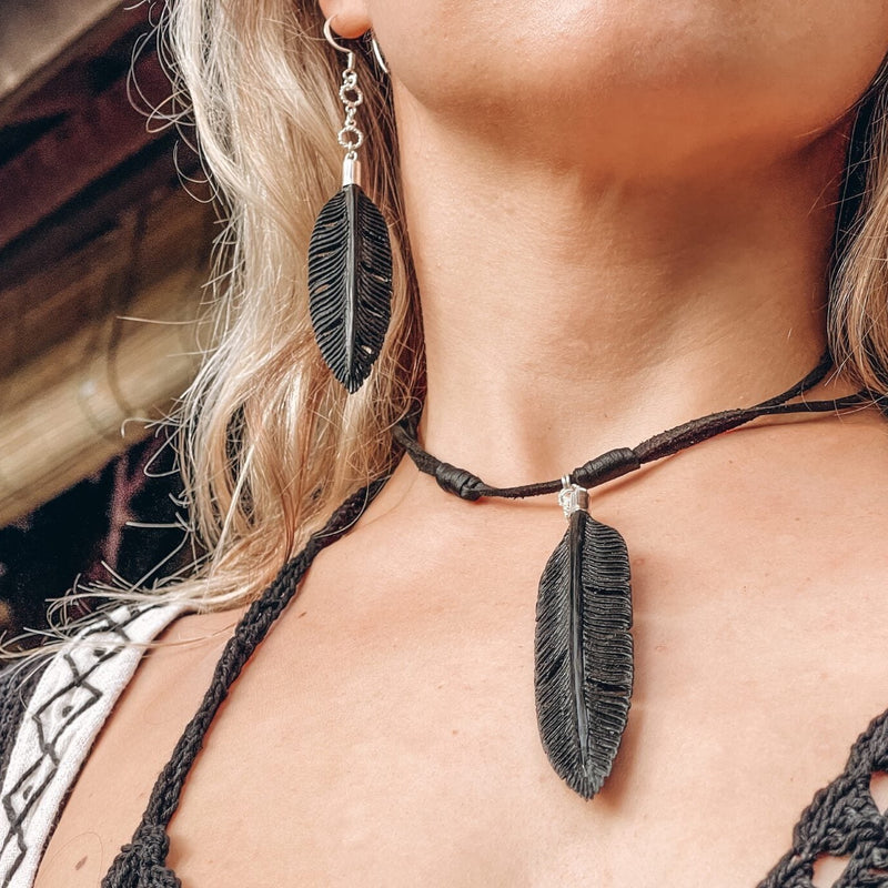 Woman wearing a black feather necklace and matching earrings, presenting a boho style with elements of shamanic jewelry, creating an aesthetic rooted in natural motifs