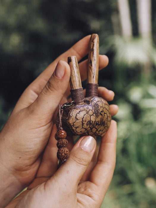 Sacred Ayahuasca vine kuripe pipe adorned with rudraksha and goldstone, a handcrafted symbol for hape snuff rituals, nestled in natural greenery.