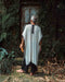 A person enveloped in a handmade Boho tribal cotton poncho, embracing the serenity of nature at a waterfall, reflecting a unisex shamanic clothing style