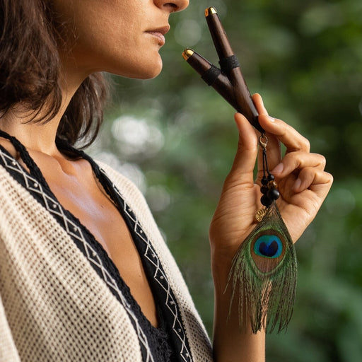 Elegant rosewood kuripe pipe necklace against a lace background, serving as both a hape snuff applicator and a unique, handcrafted piece of shamanic tools.