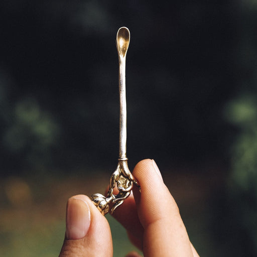 Held aloft, a premium metal Spiritual Powder Spoon intricately crafted for precise use in shamanic rituals and as a decorative element for kuripe pipes