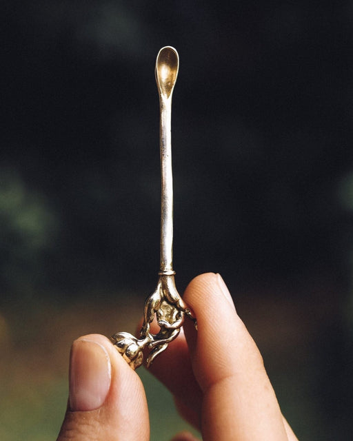 Held aloft, a premium metal Spiritual Powder Spoon intricately crafted for precise use in shamanic rituals and as a decorative element for kuripe pipes