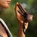 Close-up of a man using a Handmade Double Hape Kuripe, a shamanic ceremony tool for Rapé snuff application, showcasing the pipe&#39;s intricate sacred geometry and totem design for spiritual healing, meditation, and protection